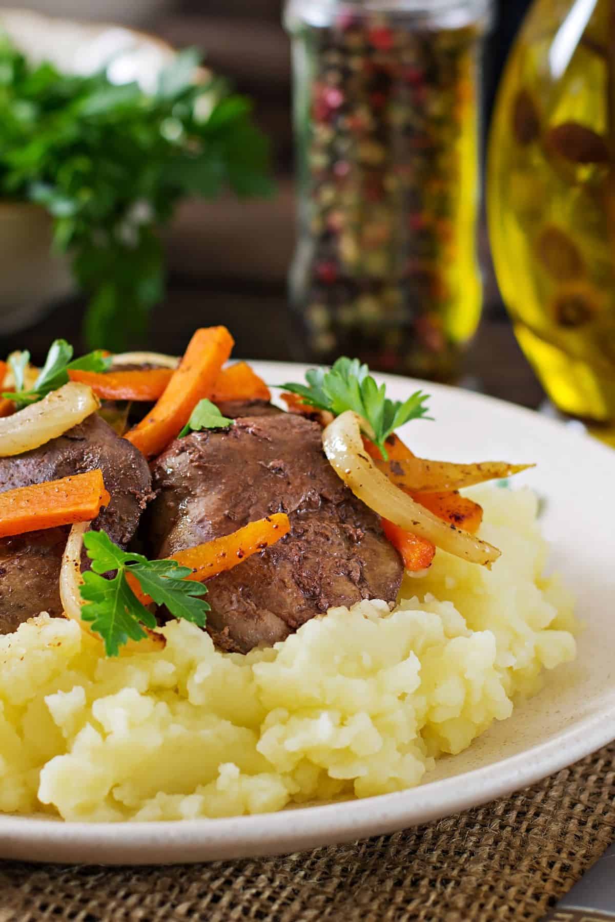 Chicken liver over mashed potatoes on a white plate